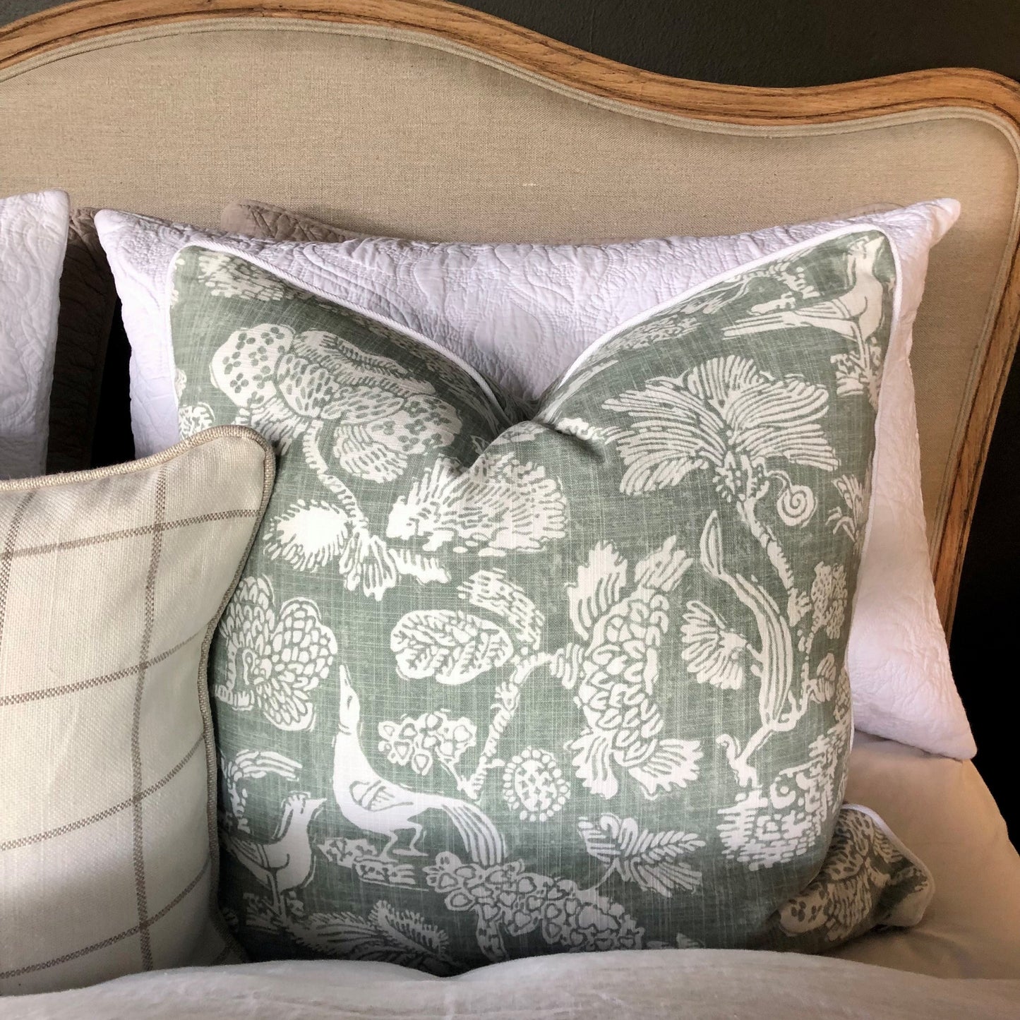This elegant Richloom Platinum Howland Linen Moss Green Cushion is crafted from Richloom's global fabric house, featuring a graceful white pattern of trees and birds on a pale green background. Its sumptuous heavyweight fabric and the luxurious feather insert make it a perfect accent for your plush home decor.