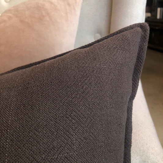 The plush feather filled Oban Herringbone Woven Stonewashed French Linen Lumbar Cushion showcases a classic herringbone pattern woven from French Linen which has been stonewashed to achieve a soft luxurious feel. Close up corner.