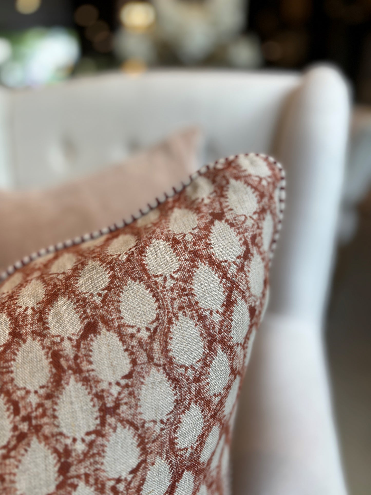 This elegant Cypress Block Printed Linen Mustard Cushion is hand block printed on soft, natural linen and adorned with delicate piping along the edges. Drawing inspiration from the luxurious textiles of the ancient Orient, it adds a touch of sophistication to any space. Crafted by the renowned Swedish brand, Chamois, this cushion is made with premium Belgian 100% linen and includes a soft feather insert. Corner close up.