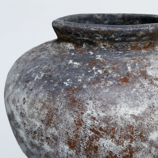 Rust-colored ceramic pot with a textured surface on a gray background