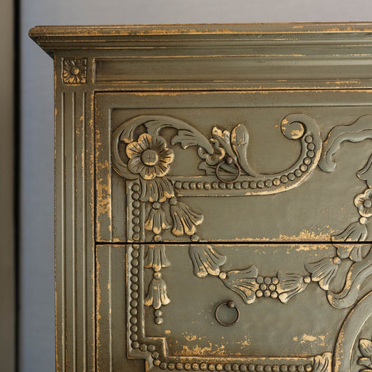 The unique and stunning one of a kind Daphne Sideboard boasts intricate carvings and distressed pale olive/grey painted finish. Crafted from mahogany and featuring two drawers, this versatile piece is perfect for a living or dining room in even in a bedroom. Detail