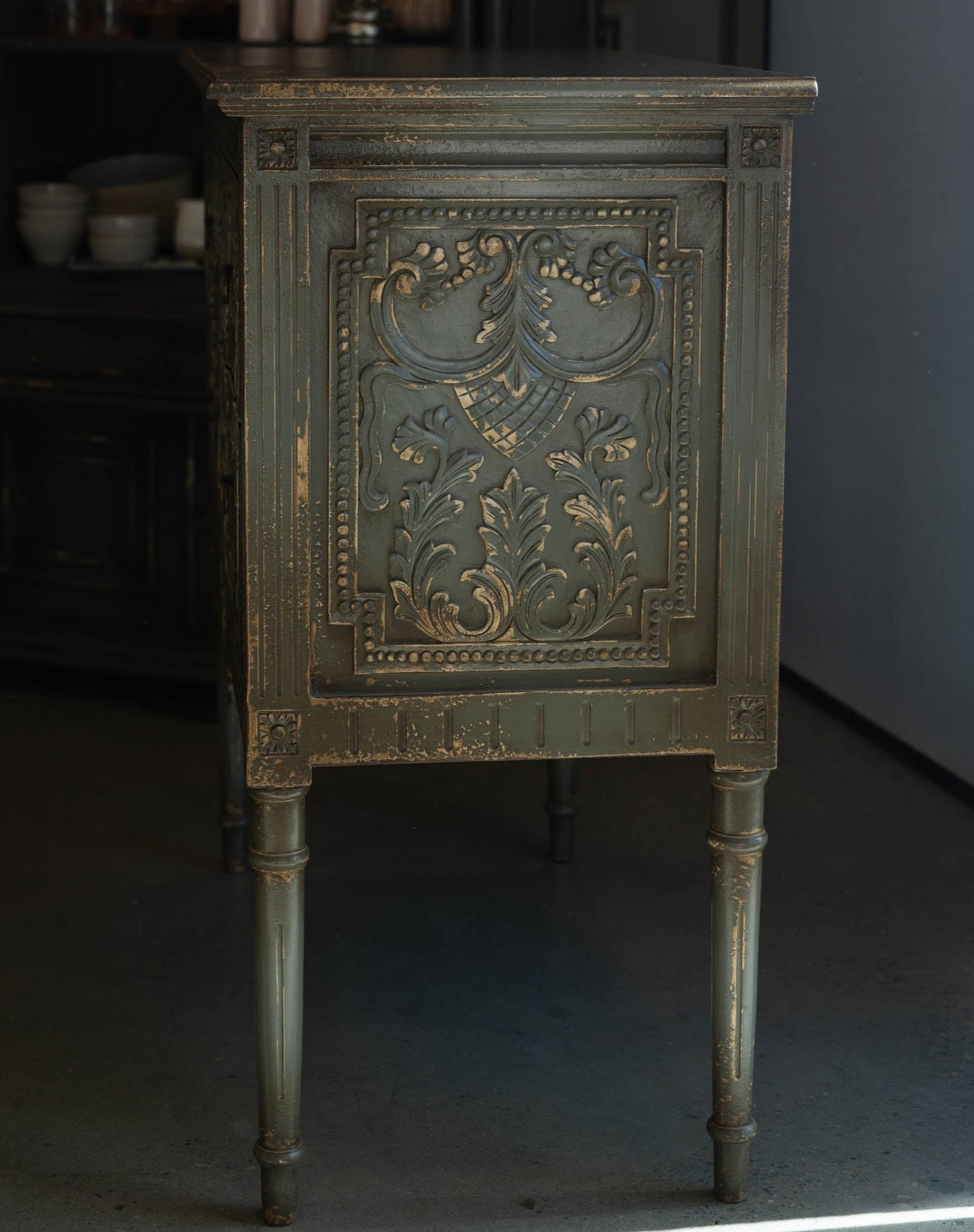 The unique and stunning one of a kind Daphne Sideboard boasts intricate carvings and distressed pale olive/grey painted finish. Crafted from mahogany and featuring two drawers, this versatile piece is perfect for a living or dining room in even in a bedroom. Side