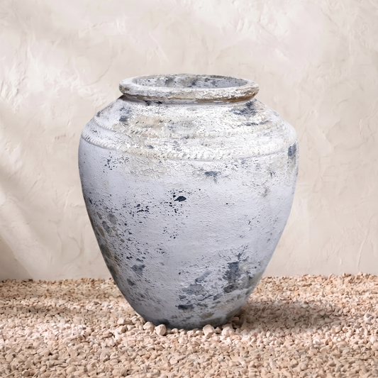 Vintage-style terracotta pot on a textured surface with a neutral background