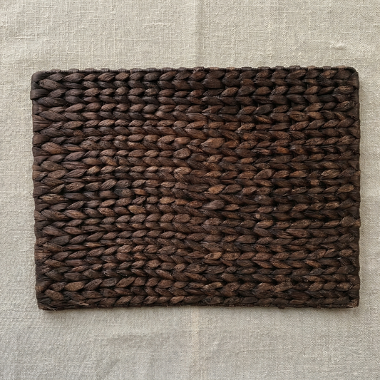 Brown woven placemat on a beige textured surface