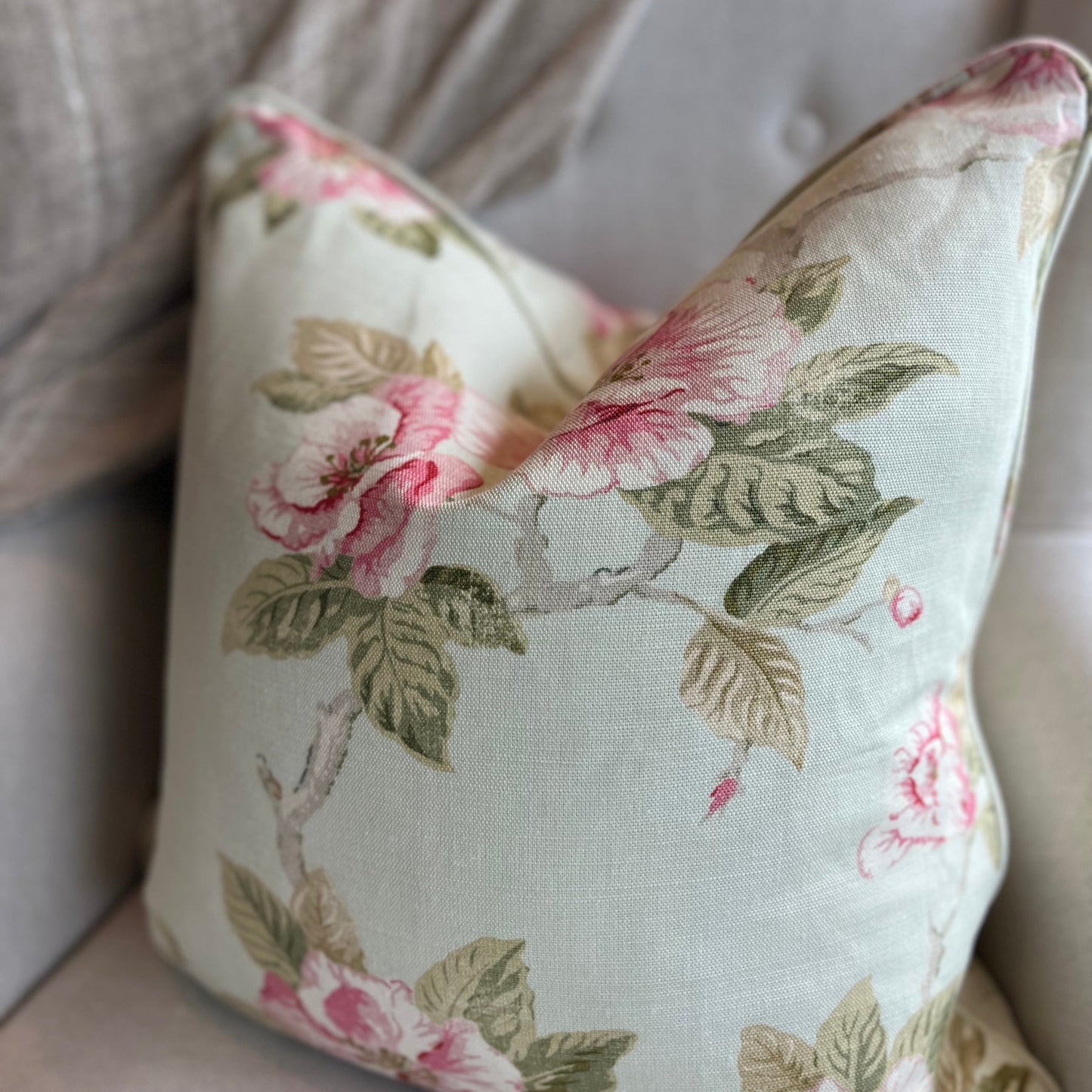 Experience the charm of the Ava Floral Print Linen Cushion - a favorite among our team. The delicate blend of sage green leaves and blush pink petals on a subtle, soft green background creates an elegant and beautiful addition to any space. Front Close-up