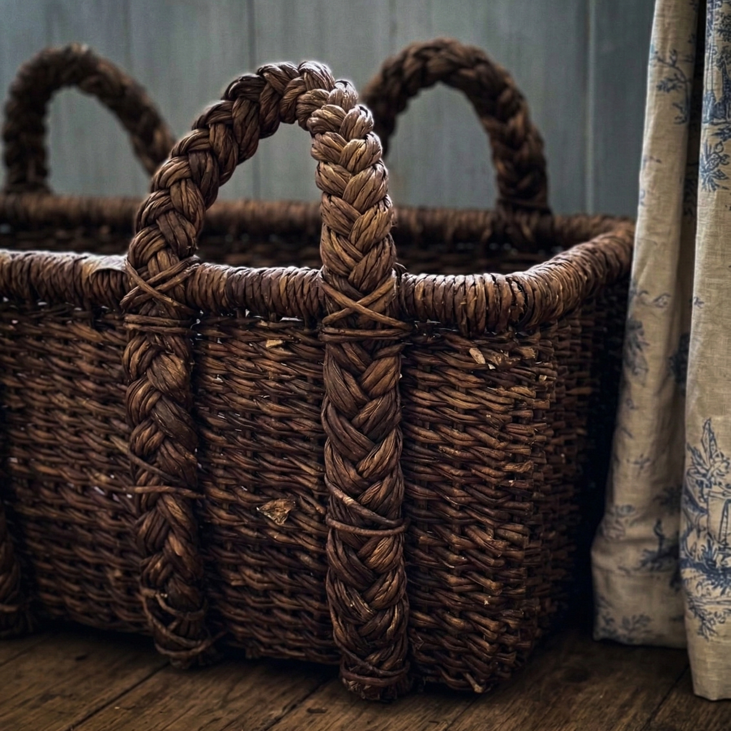 Woven basket with braided handles on a wooden floor