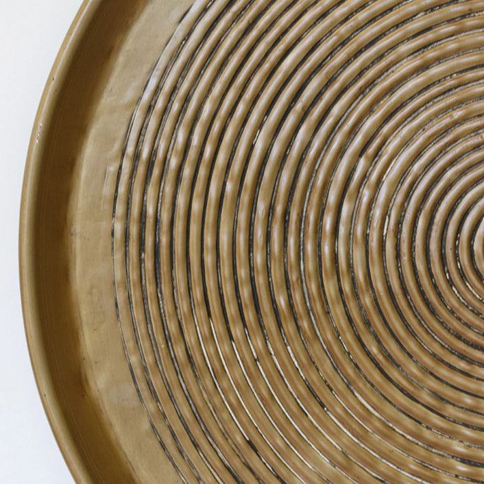 The Calypso Round Tray in Medium features a hammered antique brass finish, crafted from aluminium. Its elegant design is perfect for adding a touch of sophistication to dining tables, coffee tables, ottomans, or console decor. Whether used as a stunning serving platter or as a base for decorative displays, this tray is sure to make a statement in any home setting.