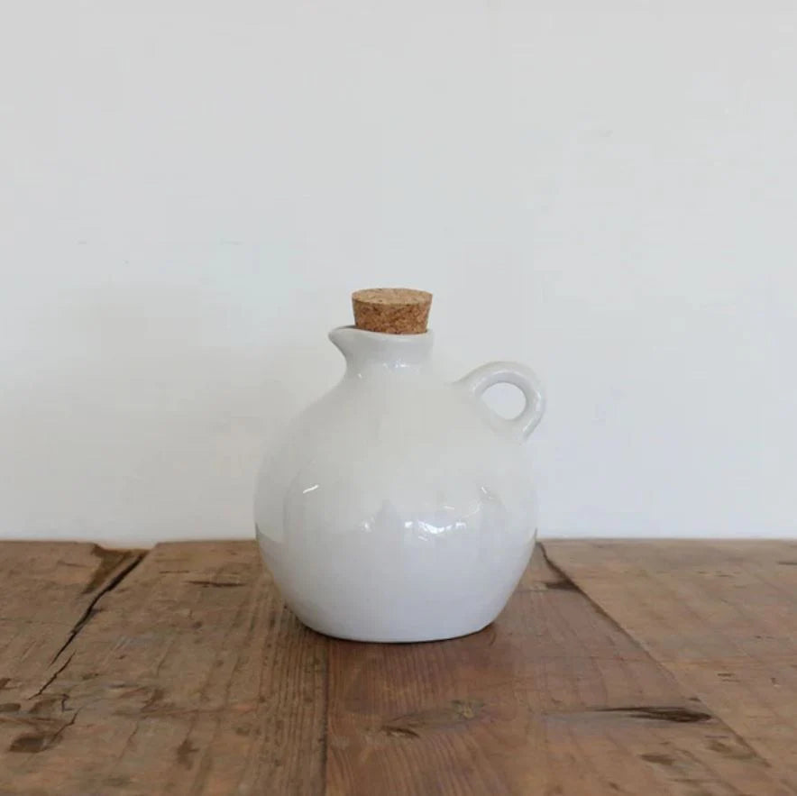 The Creamery Handcrafted Oil Pourer showcases a graceful organic shape, texture, and color that highlight its distinctive appeal. Crafted from sturdy stoneware and finished with a soft ivory cream glaze, it offers a timeless design perfect for daily use. Dishwasher, microwave, and oven safe, this elegant oil pourer combines functionality with style, making it a stunning addition to any kitchen display.