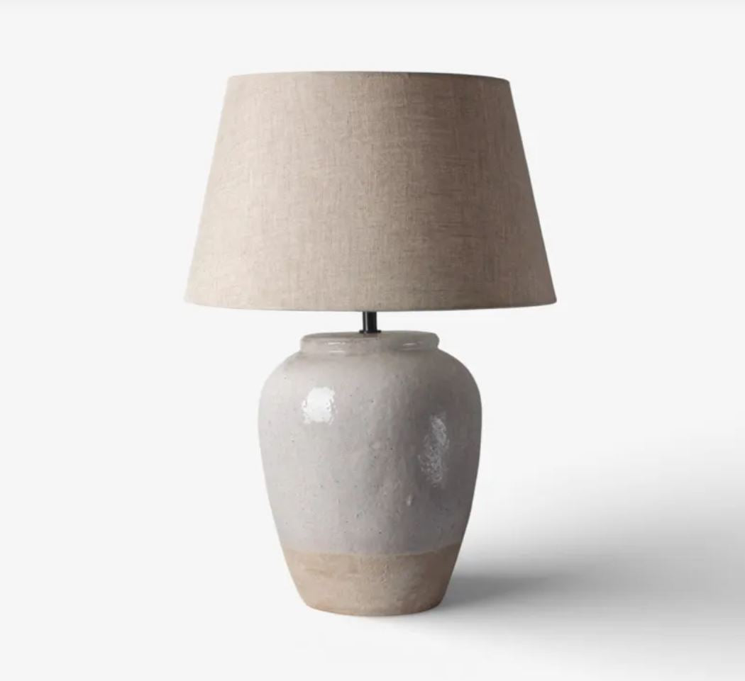 Table lamp with beige lampshade and ceramic base on a white background