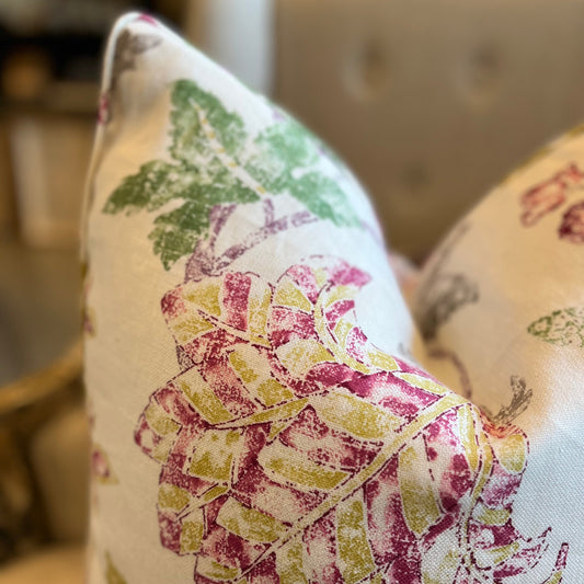 Bring a vibrant burst of color to any space with this beautiful floral print cushion. Featuring shades of raspberry pink, mustard yellow, and green against an ivory background with subtle splashes of grey. Close-up Focus