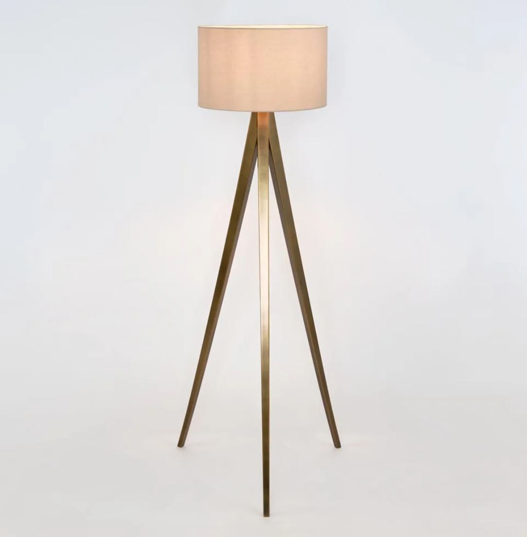 Tripod floor lamp with a beige shade on a white background