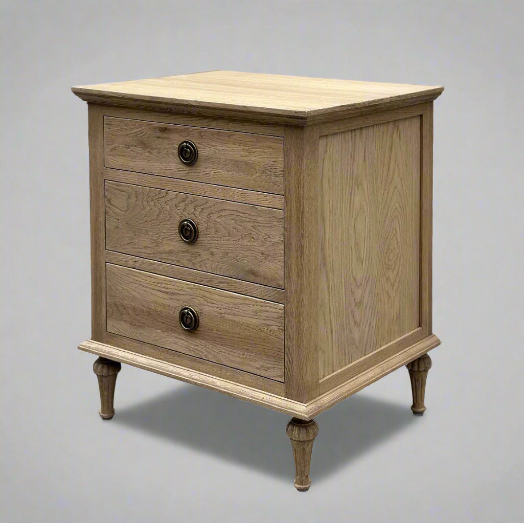 Experience the opulent design of this French Weathered Oak Bedside Table, expertly crafted from premium, solid oak wood and finished with a striking, weathered look. Featuring three drawers and adorned with elegant brass handles, this piece seamlessly blends practicality and elegance. The use of classic mortise-and-tenon joinery and dovetail drawers highlights the exceptional craftsmanship and allure of this exceptional table.