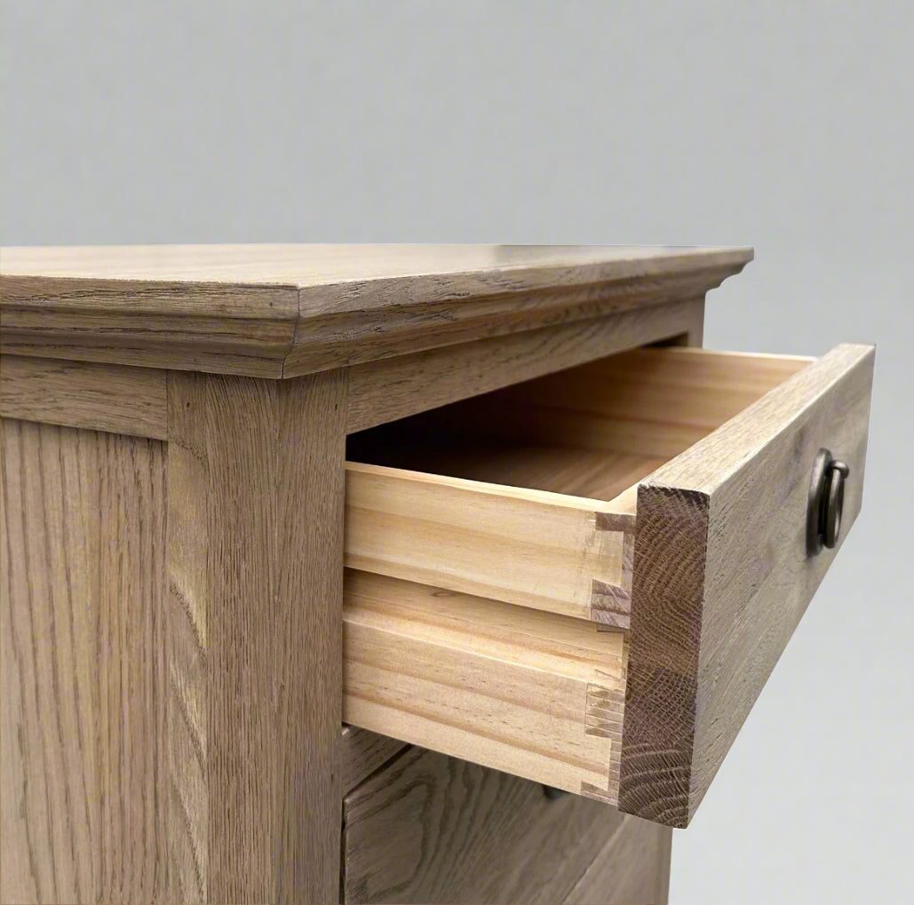 Experience the opulent design of this French Weathered Oak Bedside Table, expertly crafted from premium, solid oak wood and finished with a striking, weathered look. Featuring three drawers and adorned with elegant brass handles, this piece seamlessly blends practicality and elegance. The use of classic mortise-and-tenon joinery and dovetail drawers highlights the exceptional craftsmanship and allure of this exceptional table.