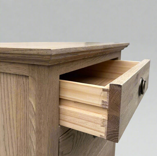 Experience the opulent design of this French Weathered Oak Bedside Table, expertly crafted from premium, solid oak wood and finished with a striking, weathered look. Featuring three drawers and adorned with elegant brass handles, this piece seamlessly blends practicality and elegance. The use of classic mortise-and-tenon joinery and dovetail drawers highlights the exceptional craftsmanship and allure of this exceptional table.