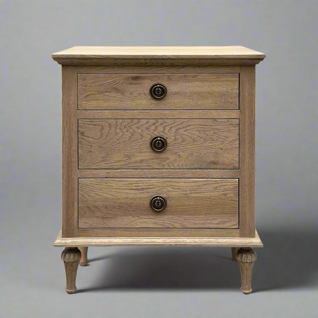 Experience the opulent design of this French Weathered Oak Bedside Table, expertly crafted from premium, solid oak wood and finished with a striking, weathered look. Featuring three drawers and adorned with elegant brass handles, this piece seamlessly blends practicality and elegance. The use of classic mortise-and-tenon joinery and dovetail drawers highlights the exceptional craftsmanship and allure of this exceptional table.