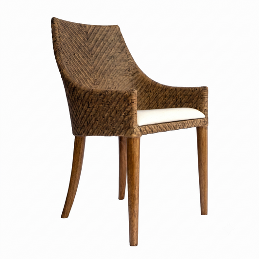 A rattan dining chair with a brown woven rattan back and armrests, a cream-colored seat cushion, and four tapered wooden legs, shown against a plain white background.