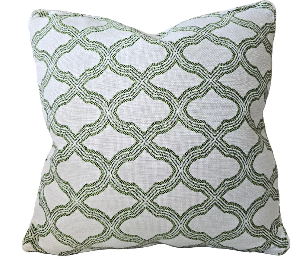 A square throw pillow featuring a green trellis pattern on a white textured fabric background, isolated on a white studio background.