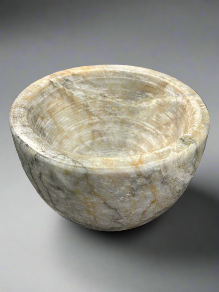 Indulge in the captivating combination of off-white, brown, and grey hues found in our Sangiran Stone Bowl. Its exquisite, handcrafted design brings a touch of sophistication to any room. Ideal for showcasing on a coffee table, console, or bedside, it also doubles as a functional holder for precious trinkets, meticulously carved by skilled artisans in Southeast Asia.