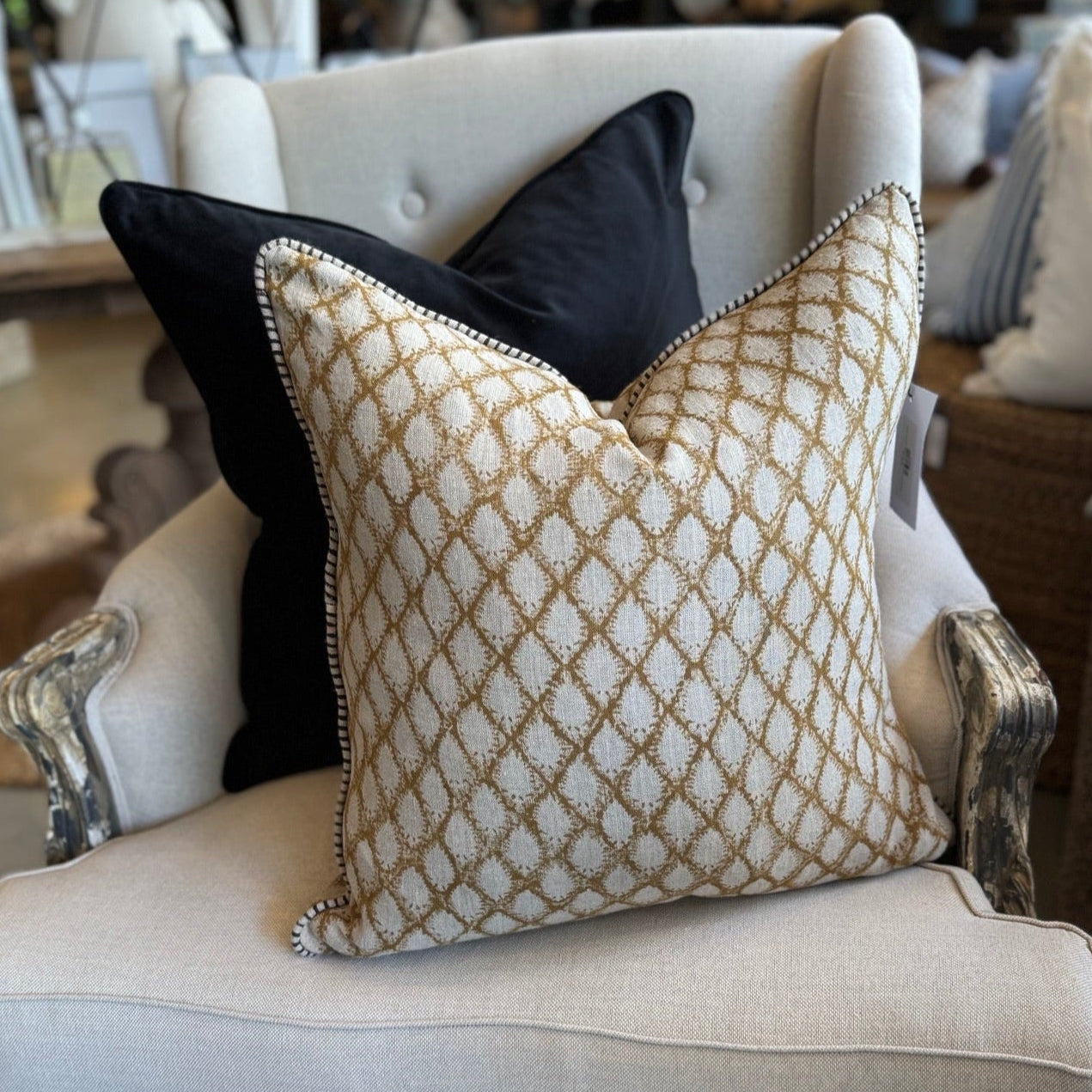 A black velvet cushion with a geometric pattern insert on a white chair.