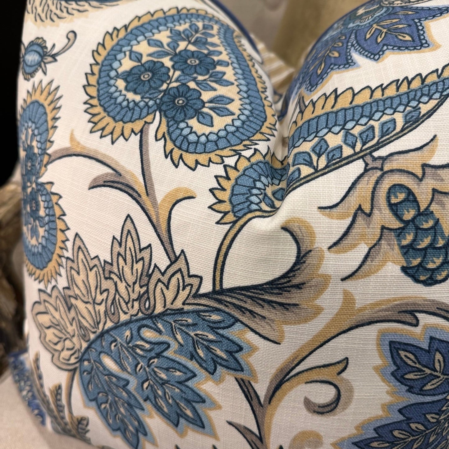 Elevate your interior with the Emily Blue & Taupe Floral Cushion, masterfully crafted using superior fabrics. The sophisticated floral pattern displays captivating blue and taupe hues on a pristine ivory canvas, drawing admiring glances in any setting. Flip to reveal a refined ochre ticking stripe complemented by rich deep blue piping for versatile styling options.