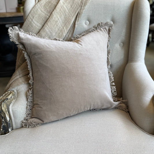 Beige pillow with fringe on a light gray armchair