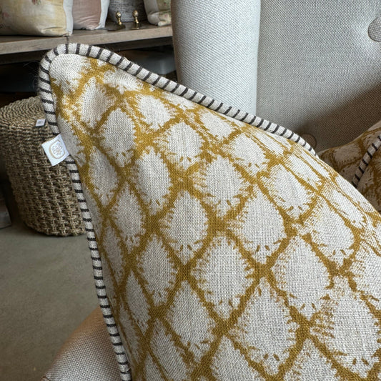 Elevate your home decor with the Cypress Block Printed Linen Ochre Cushion from CHAMOIS, a beloved Swedish brand known for their impeccable style. Crafted from premium Belgian 100% linen and featuring a soft feather insert, this cushion is a must-have for those who appreciate luxurious and high-quality design. Corner close up.