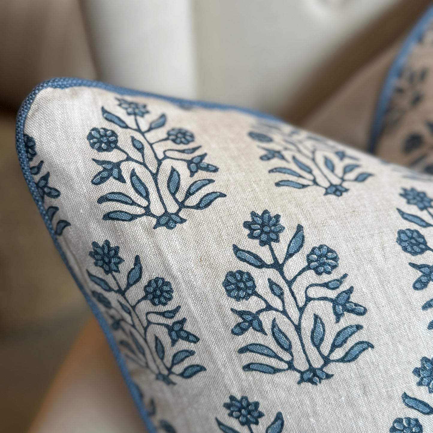 Indulge in the impeccable artistry of this high-quality Amer Azur Oatmeal Navy Floral Linen Cushion. Created by luxury textile house Walter G. and fashioned with dense, 100% linen material, it boasts a stunning navy and light blue floral pattern against an oatmeal backdrop. Complete with a feather insert for ultimate comfort. Reverse lined with oatmeal linen. Corner close up.