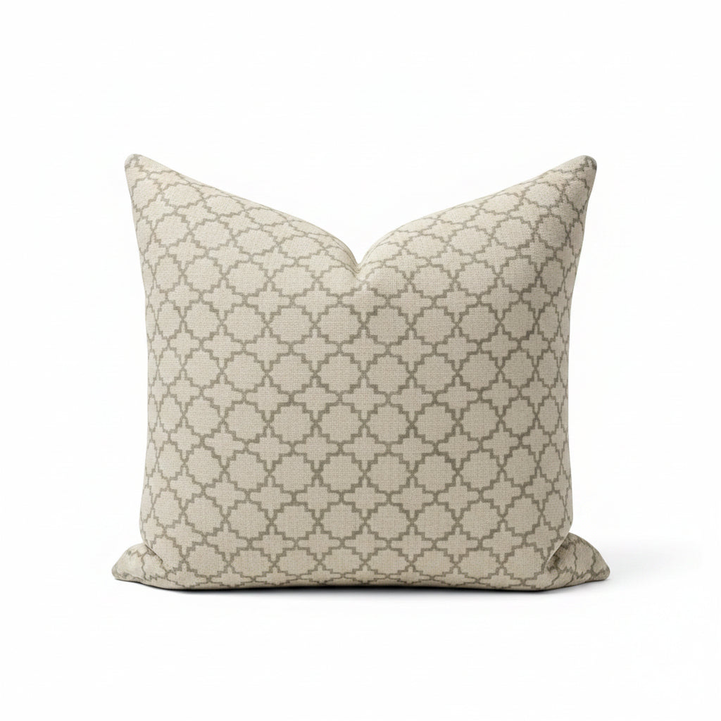 A square throw pillow with a beige and gray geometric trellis pattern, resting on a dark reflective surface.