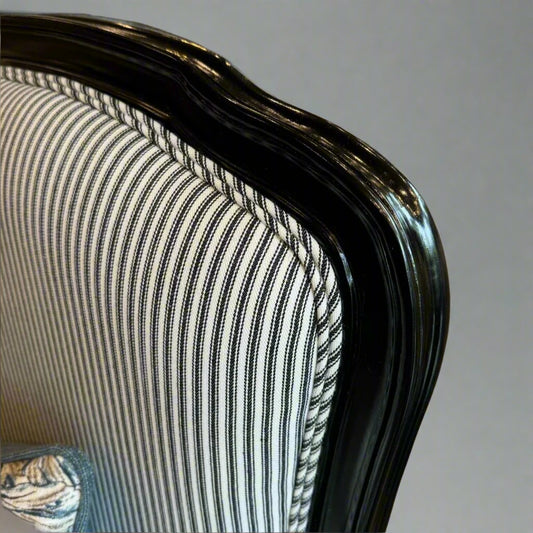 Indulge in timeless French style with this elegant armchair, exquisitely crafted from sturdy mahogany and finished with a sleek black gloss. Its luxurious hand-carved details and sturdy frame add a touch of sophistication to any living room or bedroom, while the stunning blue and white ticking fabric upholstery adds a subtle yet eye-catching touch. Elevate your space with this expertly crafted piece that exudes elegance and charm.