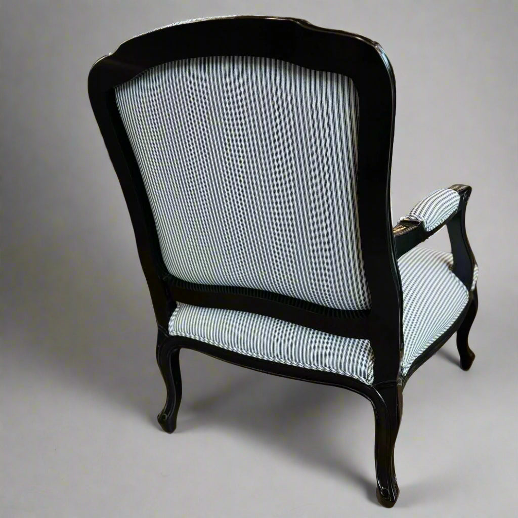 Indulge in timeless French style with this elegant armchair, exquisitely crafted from sturdy mahogany and finished with a sleek black gloss. Its luxurious hand-carved details and sturdy frame add a touch of sophistication to any living room or bedroom, while the stunning blue and white ticking fabric upholstery adds a subtle yet eye-catching touch. Elevate your space with this expertly crafted piece that exudes elegance and charm.