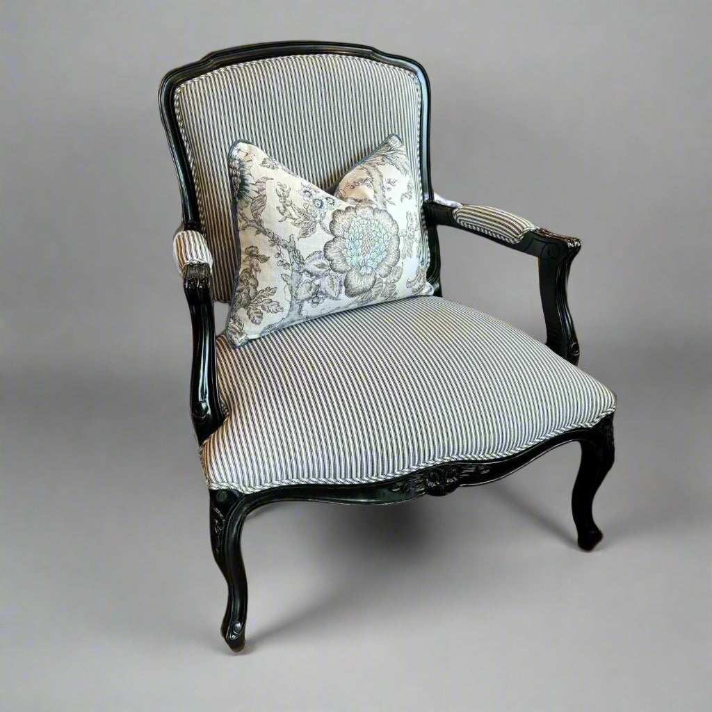 Indulge in timeless French style with this elegant armchair, exquisitely crafted from sturdy mahogany and finished with a sleek black gloss. Its luxurious hand-carved details and sturdy frame add a touch of sophistication to any living room or bedroom, while the stunning blue and white ticking fabric upholstery adds a subtle yet eye-catching touch. Elevate your space with this expertly crafted piece that exudes elegance and charm.