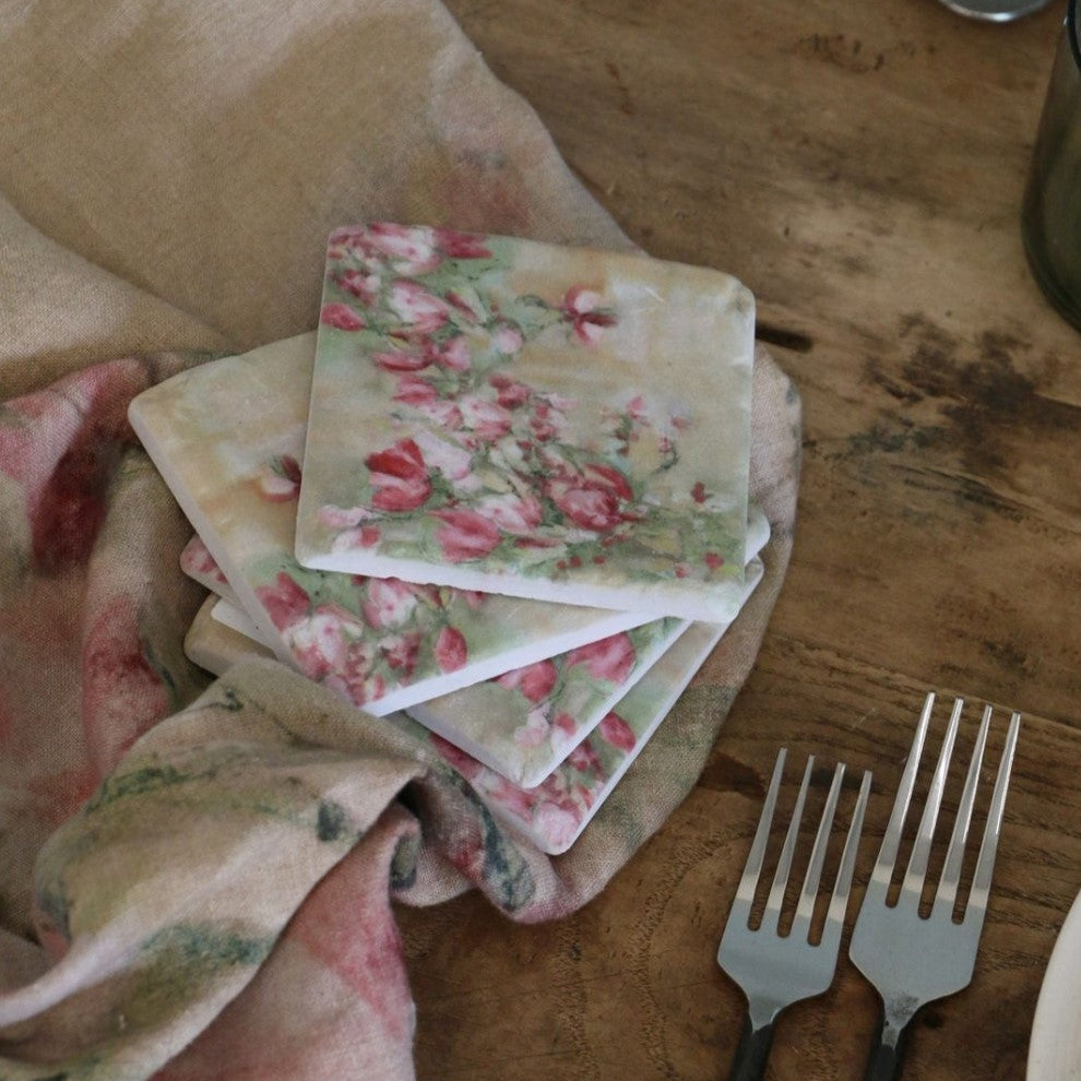 This elegant Magnolia Limone Pink Floral Coaster - Set Of 4 features vibrant pink magnolia blooms against a delicate and inviting backdrop. These coasters make a statement on any table surface while also helping protect furniture. Styled.