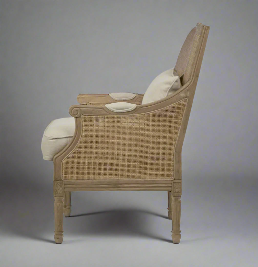 Indulge in the timeless design of this Hicks Caned Armchair with its carved oak frame, rattan back, and natural cotton upholstery. The plush seat and back cushions, both removable for easy cleaning, make it perfect for any living room or bedroom. Add a touch of elegance and comfort to your home with this must-have piece. Side