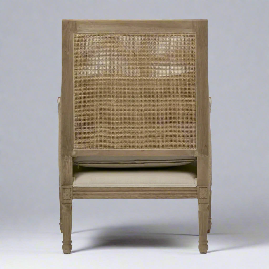 Indulge in the timeless design of this Hicks Caned Armchair with its carved oak frame, rattan back, and natural cotton upholstery. The plush seat and back cushions, both removable for easy cleaning, make it perfect for any living room or bedroom. Add a touch of elegance and comfort to your home with this must-have piece. Back
