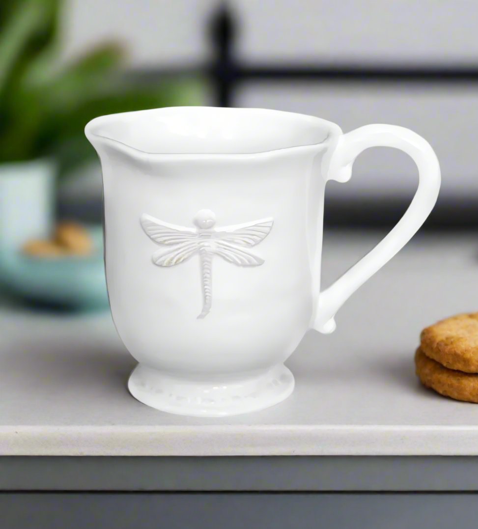 Let your morning routine take flight with our stunning Dragonfly Stoneware White Mug. The rich cream glaze and intricately embossed dragonfly design make it a true statement piece. Plus, its generous size and ergonomic shape ensure a comfortable and enjoyable drinking experience. 