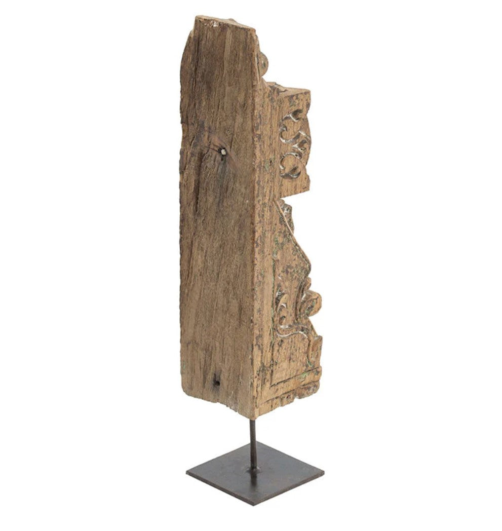 Add a touch of culture to your living room with this stunning Gujrati Toda Wood Sculpture On Metal Stand. Made with distressed wood and featuring intricate carving, it sits on a sturdy metal stand and exudes a rustic charm. Its weathered grey finish and square base give it the appearance of a museum piece, making it a perfect addition to coffee tables, bookshelves, and more.