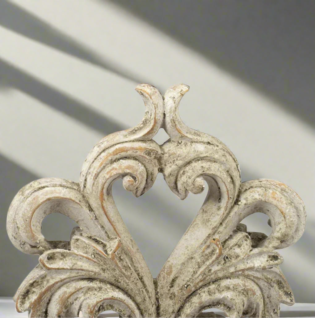 Experience the elegance and sophistication of the Crested Heart Distressed Decorative Object. With its sculptural design and subtle palette, this decorative piece made from cement is finished with a cream distressed effect. Perfect for adding personality to your decor, it will bring a touch of artistic charm to any built-ins or side table vignettes. 