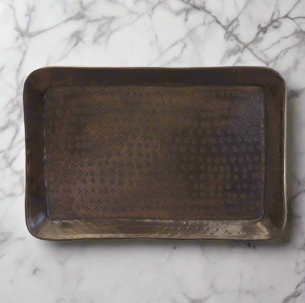 The Luxor Rectangular Tray features a hammered antique brass finish, crafted from aluminium. This versatile tray brings a beautiful warmth with it's brass finish and can be used as a statement decor piece for your home.