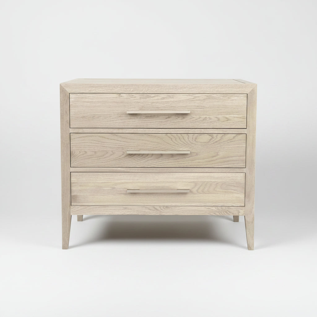 Wooden nightstand with three drawers on a light gray background