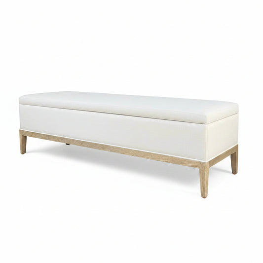 A French Contemporary End-of-bed Storage Bench with a white oatmeal linen upholstery and a wooden frame.