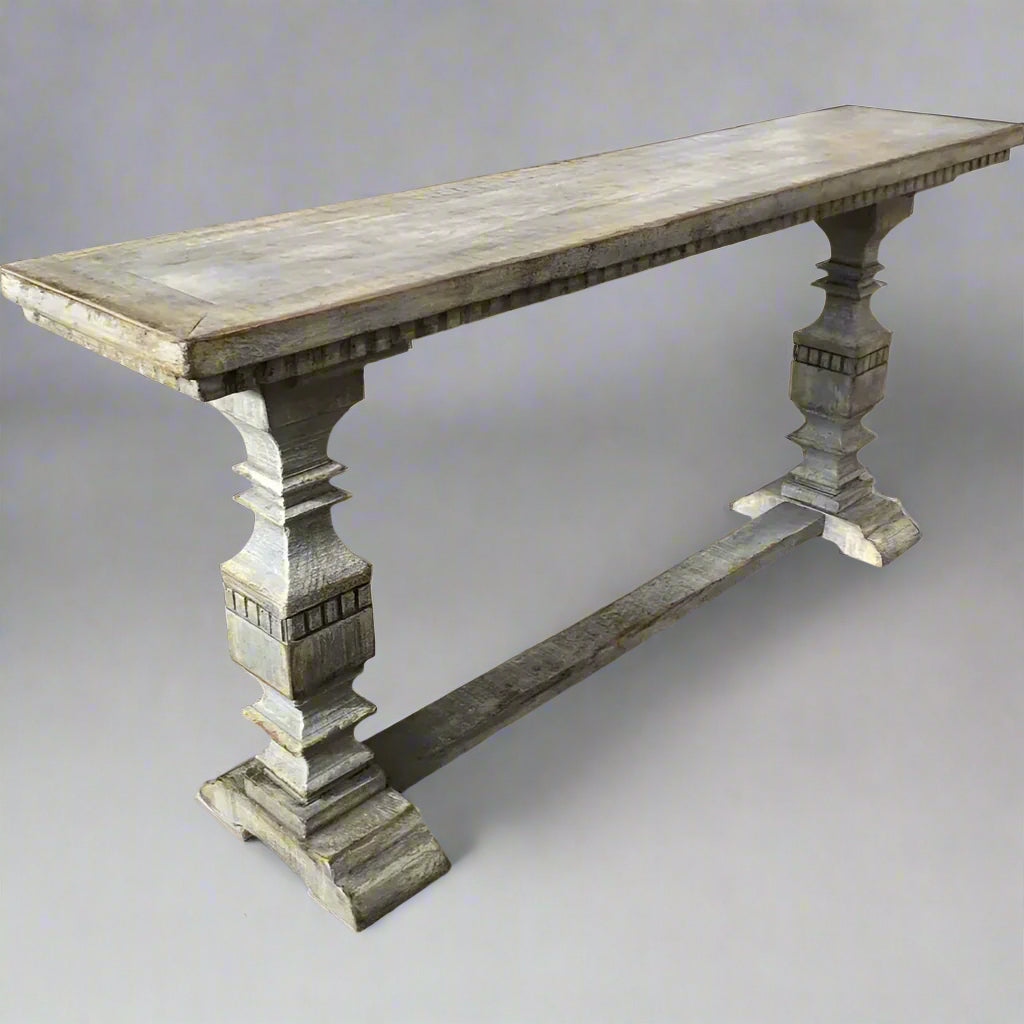 This stunning timber console table is crafted from recycled Oregon and boasts a rustic grey distressed paint finish. The intricately carved pedestal legs add a touch of elegance, making it the perfect piece to style in a hall, dining room, or behind a sofa.