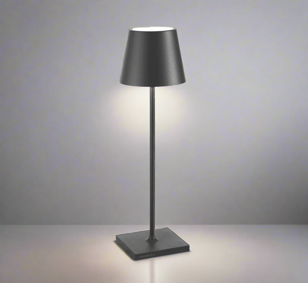 POLDINA Pro is the ultimate portable light - a must-have for any occasion. Whether you need power where you least expect it or simply prefer a clutter-free space, this lamp has got your back. Its Italian design boasts a weighted base for stability, making it suitable for any weather or surface. Take it with you for a delightful alfresco dining experience! With a rechargeable base, smart dimmer, and warm LED light, it's the perfect choice for creating a romantic ambience that lasts up to 9 hours. Power charg