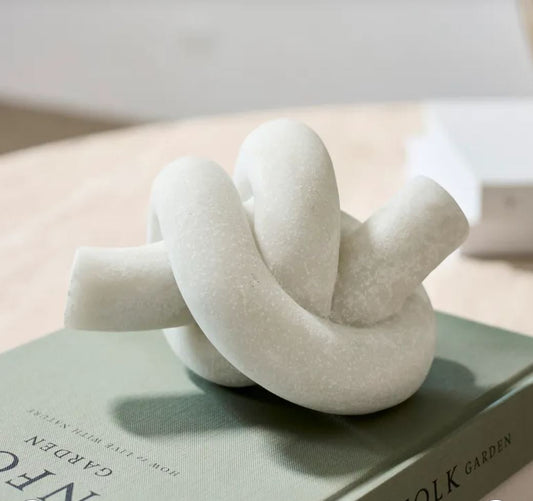 White knot-shaped object on a book with a blurred background