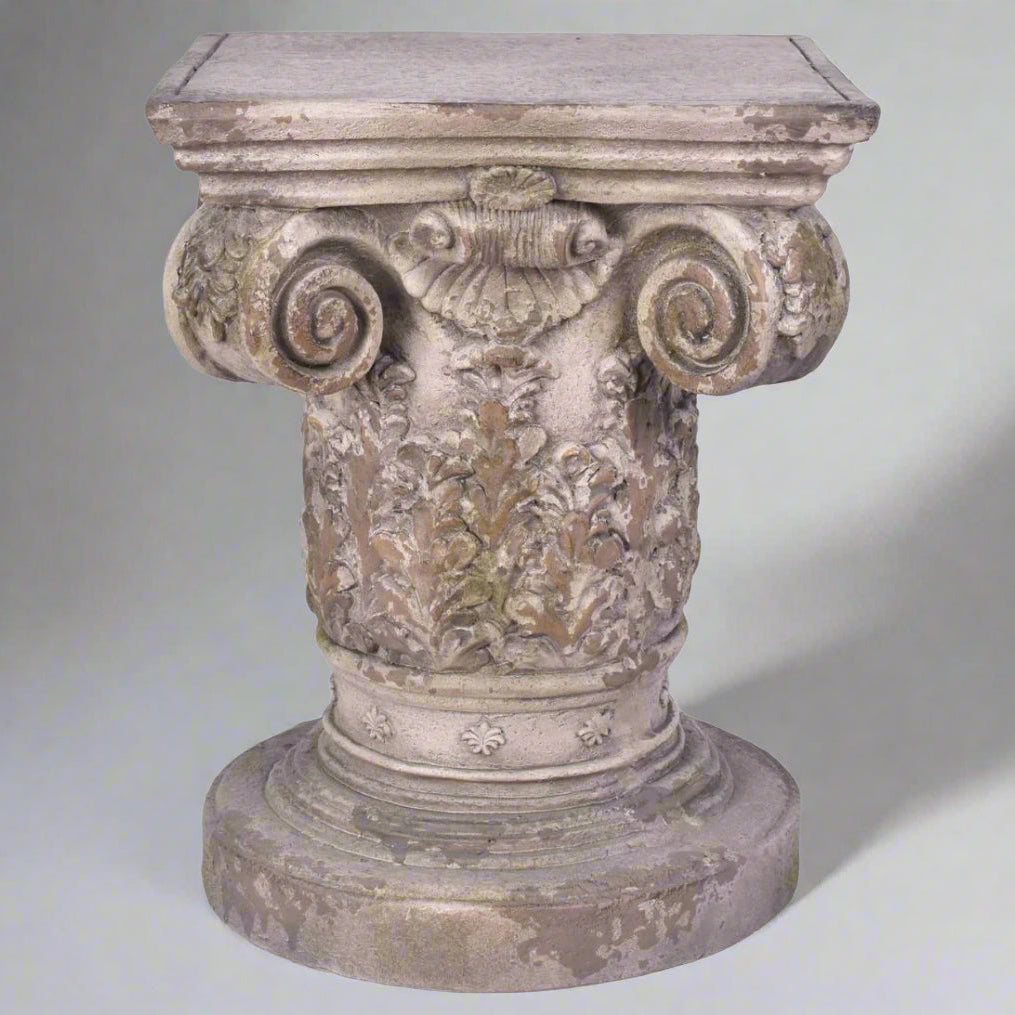 Decorative stone pedestal with intricate carvings on a white background