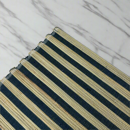 The Handwoven Diah Water Hyacinth Navy & Natural Striped Placemat - Set Of 4 are sure to elevate any table setting. Crafted from Water Hyacinth with a classic pattern, they can easily fit into many palettes, while providing protection to your tabletops. Corner close up.