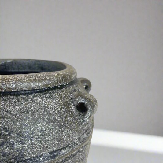This textured vase exudes a rustic, classic charm with its traditional shape. Crafted from high-quality terracotta in South East Asia, it features a distressed and hand-painted grey and black finish. Use it as a standalone decorative piece or fill it with florals and greenery for a stunning display.