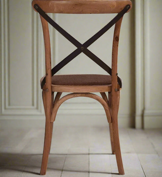 Fashioned with a sturdily crafted Oak frame and adorned with aged metal straps, the Lyon Crossback Chair features a rattan seat to enhance its visual aesthetic. Back