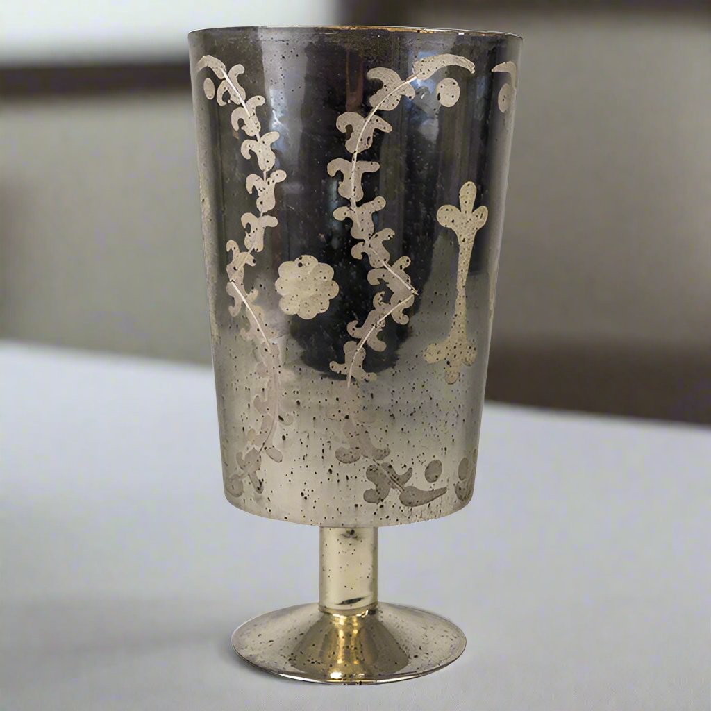 Experience the vintage-inspired charm of the Marcello Etched Mirrored Hurricane. With its elegant etched glass and mirrored silver finish, this hurricane is perfect for adding a touch of sophistication to any room. Whether displayed alone or in a pair, it's sure to bring warmth and ambiance with its ability to hold a single 3x4" candle. Illuminate your home in style with this stunning hurricane.