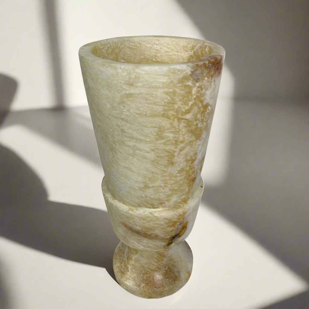 Elevate your space with the artistry of this hand-carved, smooth-textured Onyx Vase. Its unique, naturally-formed color veins and solid stone construction make a bold statement in any display. Indulge in the luxurious, gallery-quality craftsmanship of this Grand Onyx Vase.