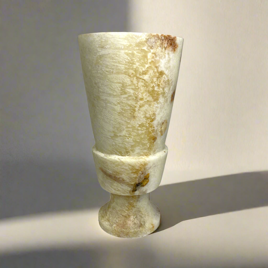 Elevate your space with the artistry of this hand-carved, smooth-textured Onyx Vase. Its unique, naturally-formed color veins and solid stone construction make a bold statement in any display. Indulge in the luxurious, gallery-quality craftsmanship of this Grand Onyx Vase.